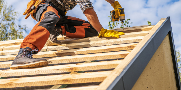 A contractor installing roof framing with a power drill